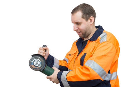 The photo depicts a man in overalls with a grinder