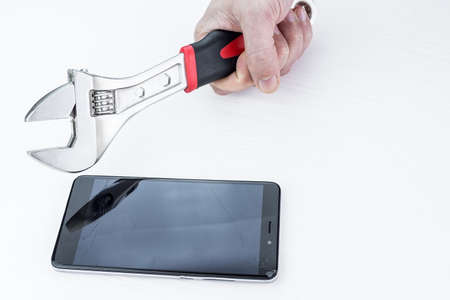 Man smashes phone with a wrench on a white backgroundの写真素材