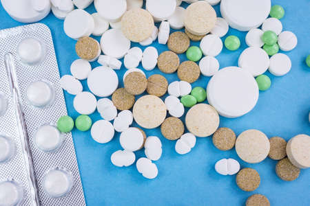 Assorted pharmaceutical medicine pills, tablets and capsules over blue backgroundの写真素材