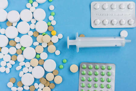 Assorted pharmaceutical medicine pills, tablets and capsules over blue background