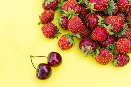 fresh strawberries and cherries on a yellow background