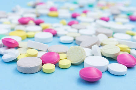 Assorted pharmaceutical medicine pills, tablets and capsules over blue backgroundの写真素材