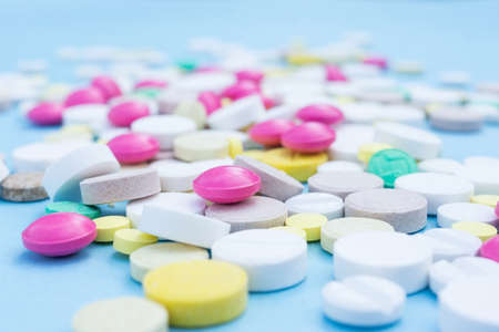 Assorted pharmaceutical medicine pills, tablets and capsules over blue backgroundの写真素材
