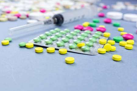 Assorted pharmaceutical medicine pills, tablets and capsules over blue background