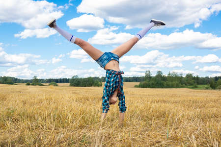 Girl gymnast does the wheel on nature in field