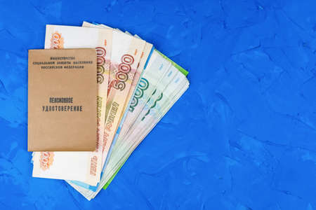 Pension certificate of Russian citizen against background of banknotes and coins. Concept of pension reform.の写真素材
