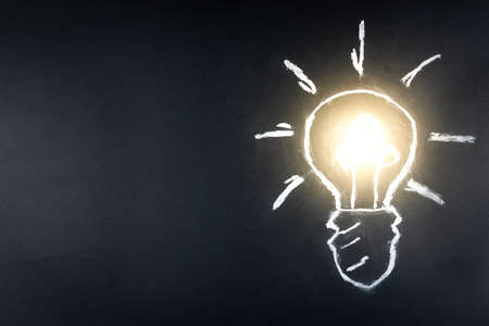 Lightbulb drawn in chalk on blackboard drawing light Bulb on black background