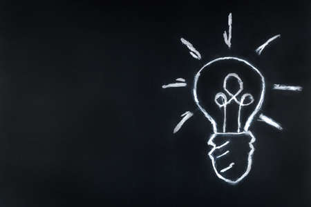 Lightbulb drawn in chalk on blackboard drawing light Bulb on black background
