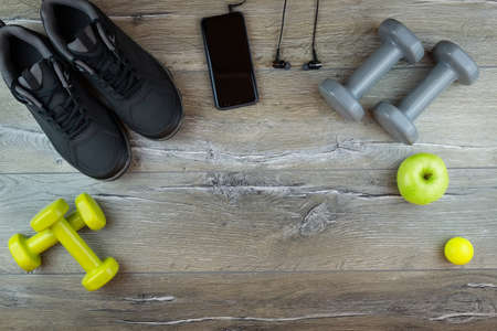 Fitness equipment. Sneakers, water, dumbbells and headphones on grey backgroundの写真素材