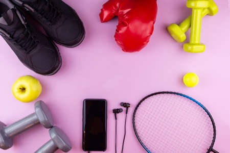 Fitness equipment. Sneakers, water, dumbbells and headphones on pink backgroundの写真素材