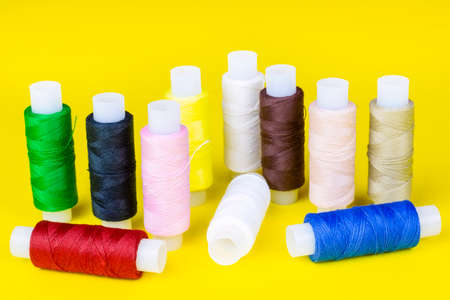 multicolored spools of thread on a yellow background, sewing kitの写真素材