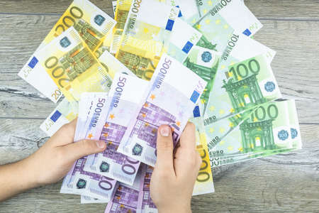hand men holding Euro bills on a gray background, the man throws money