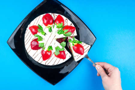 Strawberry cake with white chocolate on a black plate blue background, Cream strawberry cakeの写真素材
