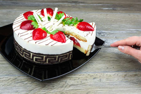 Strawberry cake with white chocolate on a black plate gray background, Cream strawberry cake