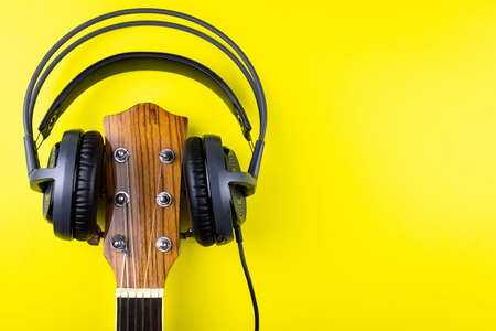 Guitar neck with headphones on yellow background, guitar Headphones on yellow textureの写真素材