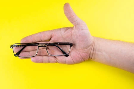 Men's hand holding glasses on yellow backgroundの写真素材