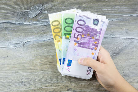 hand men holding Euro bills on a gray background, the man throws moneyの写真素材