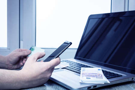 Photo businessman working with generic design notebook. Online payments, banking, hands keyboard. Businessman holding smartphone in hand and credit cardの写真素材