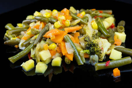 Stewed vegetables on a plate on a black background, vegetable stew on a black backgroundの写真素材