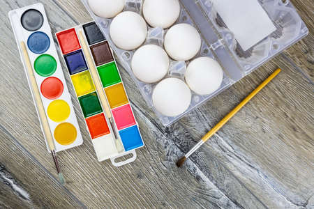 White eggs, paints, tassels, preparation for coloring for Easter.