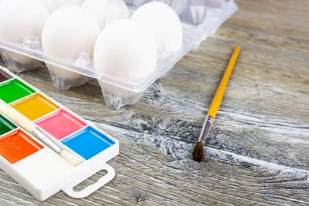 White eggs, paints, tassels, preparation for coloring for Easter.