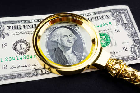 magnifying glass lies on american dollars on black background