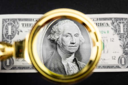 magnifying glass lies on american dollars on black background