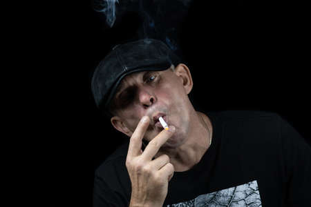 A handsome young man with a cigarette in the cloud of smokeの写真素材