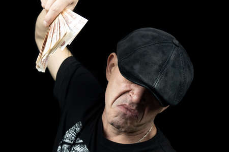 Confident attractive businessman isolated over black background, showing money banknotes, thumbs up