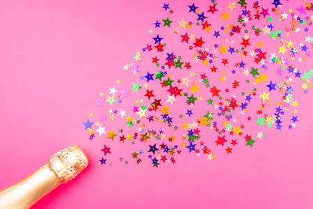 Champagne bottle with colorful sprinkles on pink backgroundの写真素材