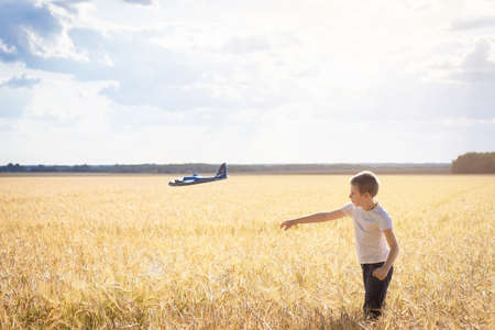 Child playing with airplane toy, boy imagines discovery adventure, blue sky backgroundの写真素材