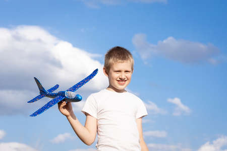 Child playing with airplane toy, boy imagines discovery adventure, blue sky backgroundの写真素材