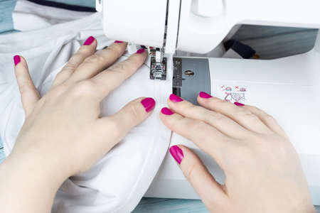 the process of tailoring, woman's hands with a cloth on the sewing machine