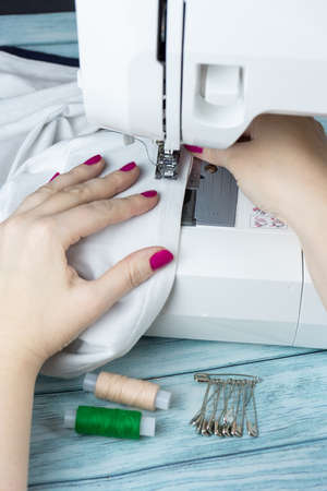 the process of tailoring, woman's hands with a cloth on the sewing machineの写真素材