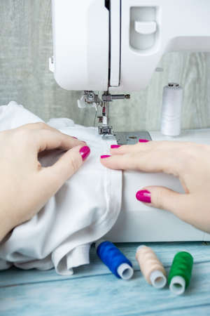 the process of tailoring, woman's hands with a cloth on the sewing machine