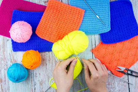 Balls of thread and female hands knit on a wooden table. Handmade concept.の写真素材