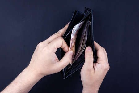 A man is holding an open wallet with money in his hands. Hands take out bills from his wallet. The concept of rejection of paper money, inflation, financial crisis.の写真素材