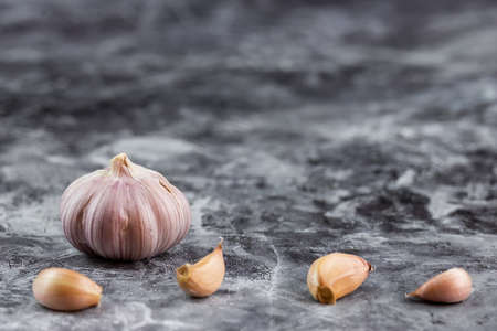 Fresh garlic on vintage table. Peeled garlic bulb and gloves on granite textureの写真素材