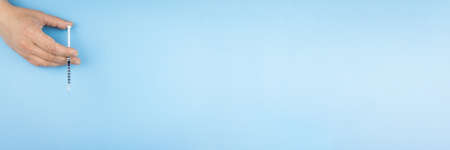 Syringe in hand on a blue backgroundの写真素材