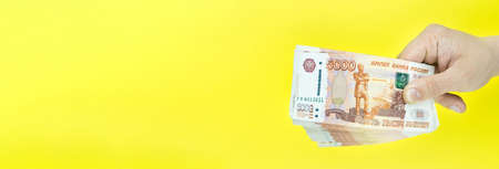 Russian money in hand on yellow background