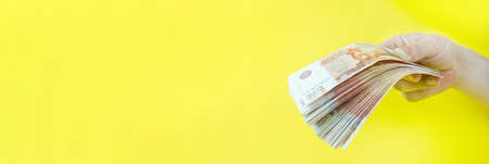 Russian money in hand on yellow background