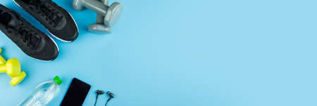 Fitness equipment. Sneakers, water, dumbbells and headphones on blue backgroundの写真素材