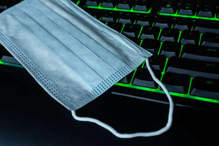 A surgical mask is placed on the keyboard of a laptopの写真素材