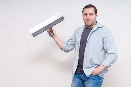 Plasterer home improvement handyman worker with putty knife working on apartment wall fillingの写真素材