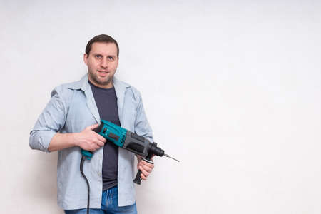 smiling handsome young male construction worker repairman with puncher on white backgroundの写真素材
