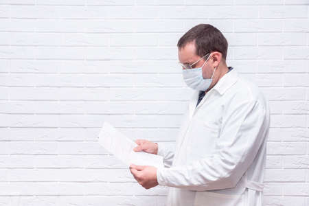 Close up of male cardiologist doctor or medical student in white coat and reading ekg paper print report of heart disease patientの写真素材