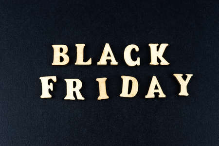 Black friday, discounts and season sales concept. Banner with grocery cart and words BLACK FRIDAY made from wooden letters on a black background. Top view, flat lay.の写真素材
