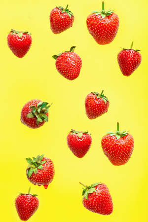 Falling strawberry isolated on yellow background, selective focusの写真素材