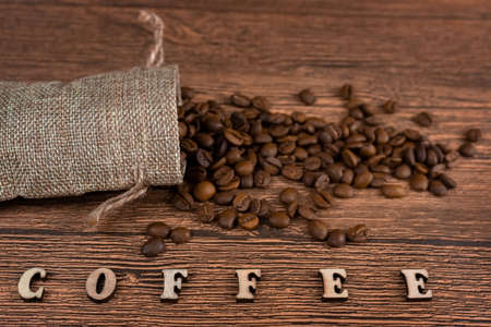 a cup of coffee and coffee beans in a bag on a dark background, top view