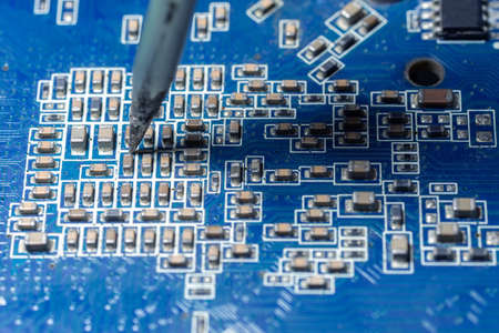 The hand holding the tin, a soldering iron solder the chip in place. computer repair. macro...